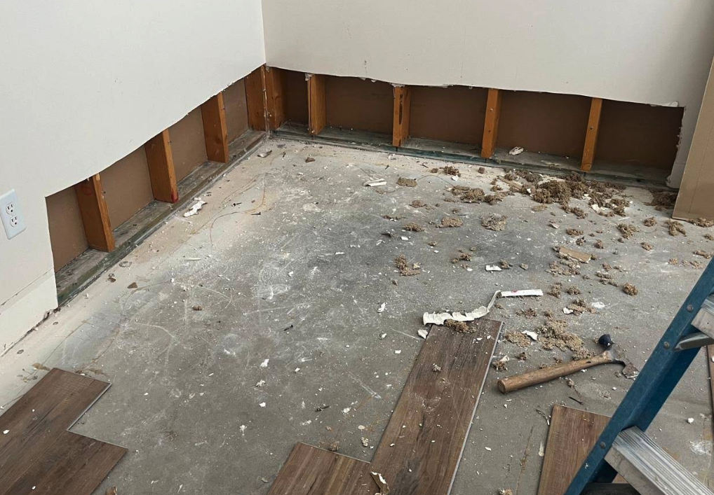 Bottom corner of wall with drywall damage before repair
